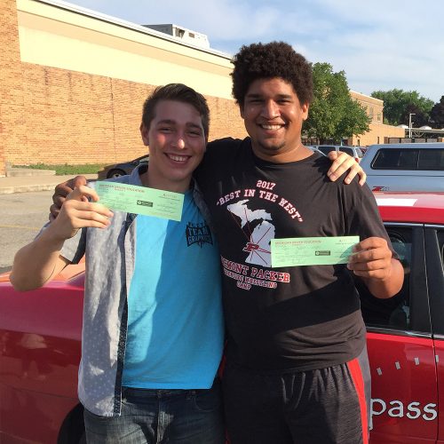 Two male Compass driving students holding up certificates excitedly